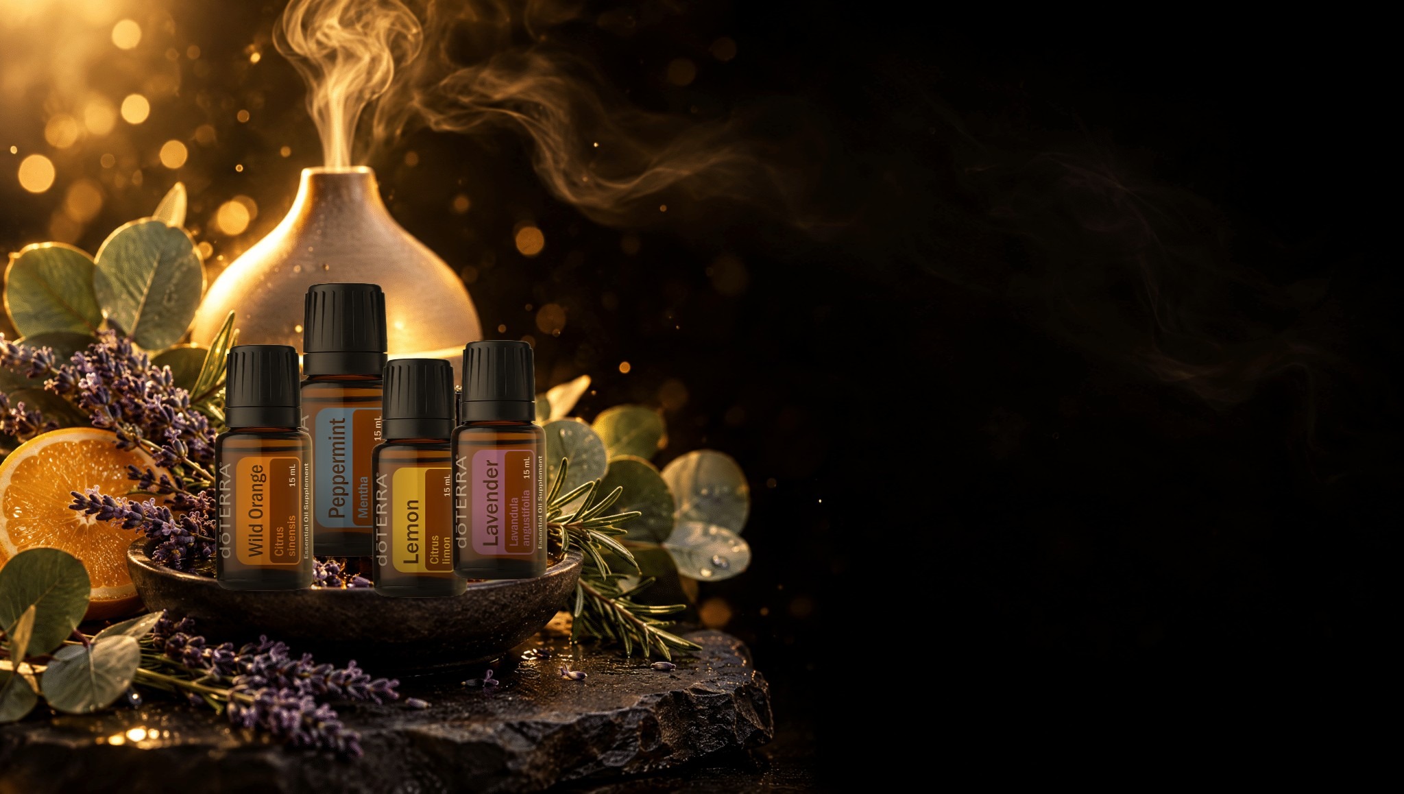 Vier originale doTERRA Öle – Wild Orange, Peppermint, Lemon und Lavender – in einer Steinschale vor einem Aroma-Diffuser mit Lavendel, Eukalyptus und Orange in warmem Goldlicht